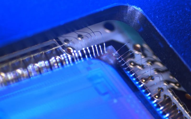 The inside of semiconductor chip under high magnification showing exposed bare wires and the silicon die. 