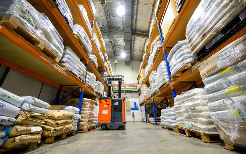 A forklift truck operating inside a warehouse used to store resin for plastic injection moulding.