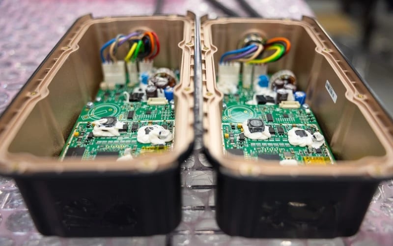 Two black metal enclosures housing green PCBAs with cables assembled.