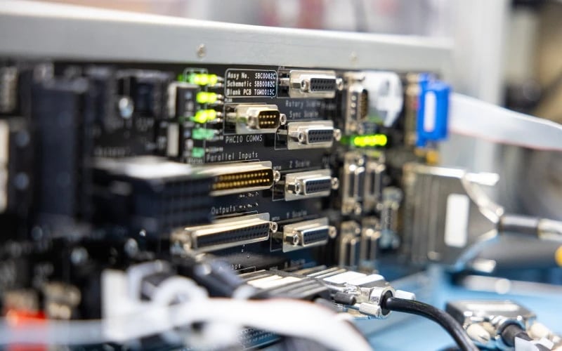Nahaufnahme der Rückseite eines komplexen Desktop-Computer-Steuerungssystems mit vielen elektronischen Anschlüssen und Kabeln.